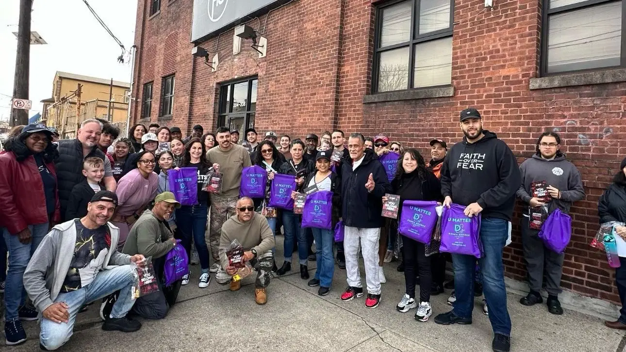 A large outreach team on a city sidewalk holding purple U Matter bags
