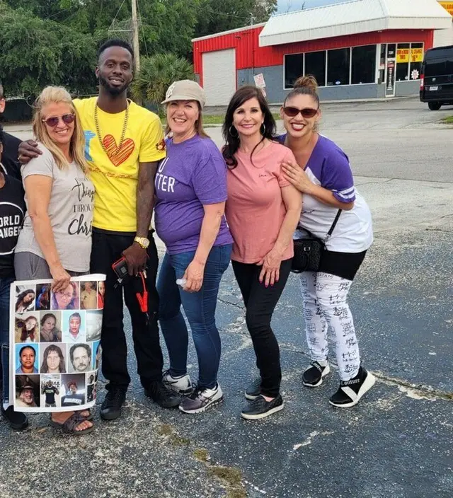 An outreach team on a street corner holding photo posters